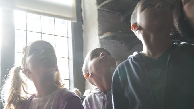 Tri o blant yn sefyll o flaen ffenestr olau, sydd â chysgodlen lliw hufen wedi ei dynnu hanner ffordd i lawr.